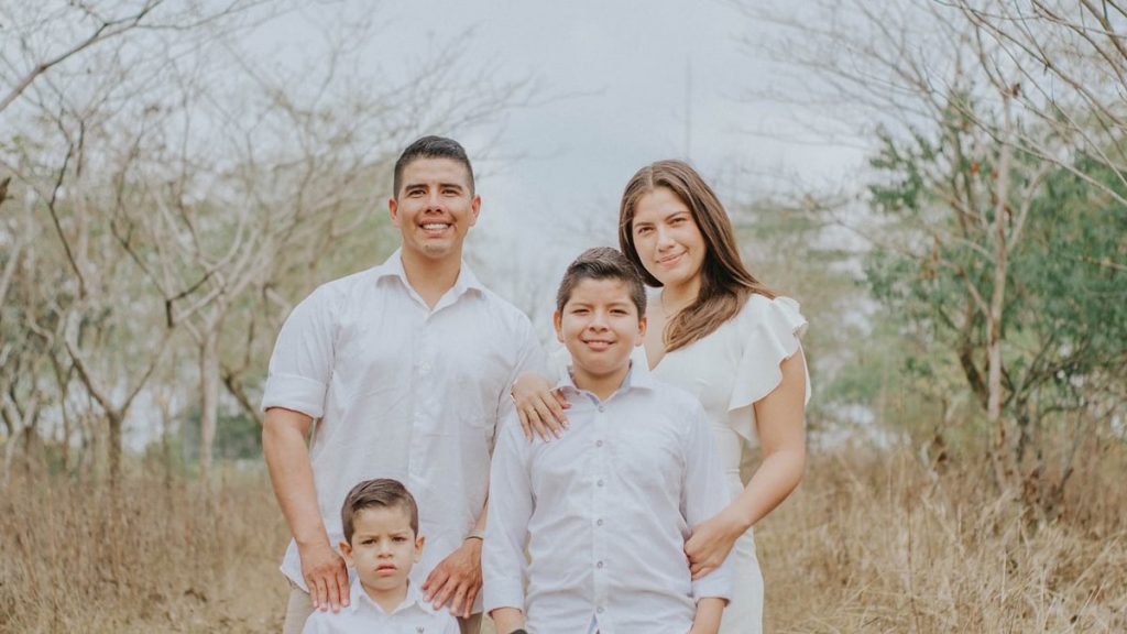 A joyful family poses together in a serene countryside setting, showcasing warmth and togetherness.